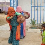 Rural women return home after collecting clean drinking water from a filtration plant in Sarmast village