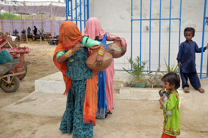 Rural women return home after collecting clean drinking water from a filtration plant in Sarmast village