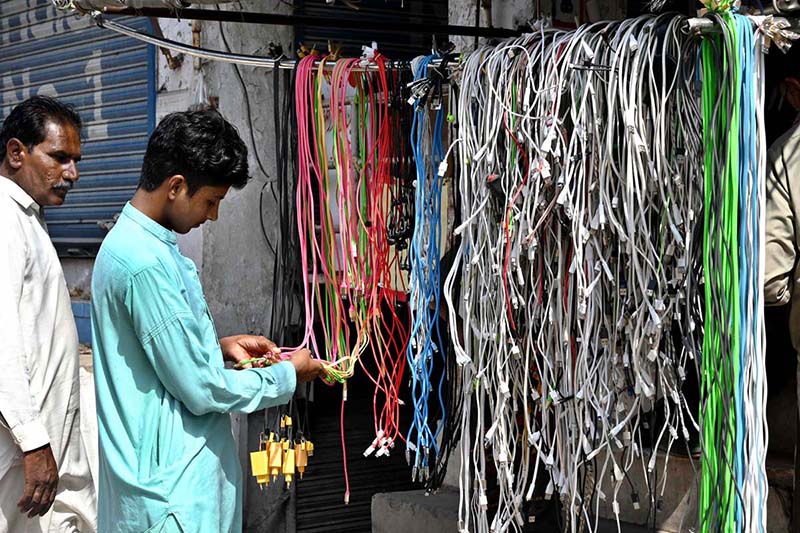 A young man is selecting mobile phone cables on Hall Road