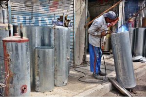 A worker welds geysers at his shop as demand rises with the onset of the winter season.