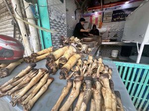 A vendor cutting paye (cow trotters) for customers at Bani Market.