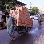 A labourer drives a loaded-cart on a busy road at Tower area
