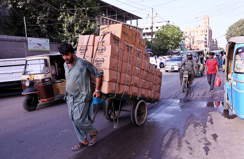 A labourer drives a loaded-cart on a busy road at Tower area