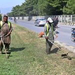 A CDA worker busy trimming grass along the roadside greenbelt in the Federal Capital