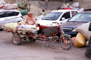 A labourer drives a loaded-cart on a busy road at Tower area