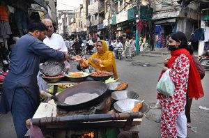 People drink fresh juice made from seasonal mausambi (sweet lime) prepared by a fruit vendor