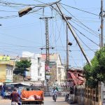 An electricity pole leans dangerously towards the road, posing a potential risk to commuters in Latifabad Unit No. 7
