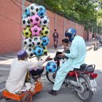 An elderly, disabled vendor sells balls by the roadside to earn a livelihood for his children in the city