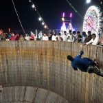 Stunt biker perform in the Well of Death as spectators watch during the Dada Hanjer Pir local Mela at a fairground near Multan Road