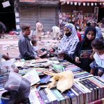 Women browse and purchase books from a street vendor’s cart in the Saddar area