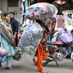 A woman carries cotton-filled quilts (razais) as the weather begins to turn cooler in the city