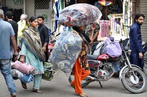 A woman carries cotton-filled quilts (razais) as the weather begins to turn cooler in the city