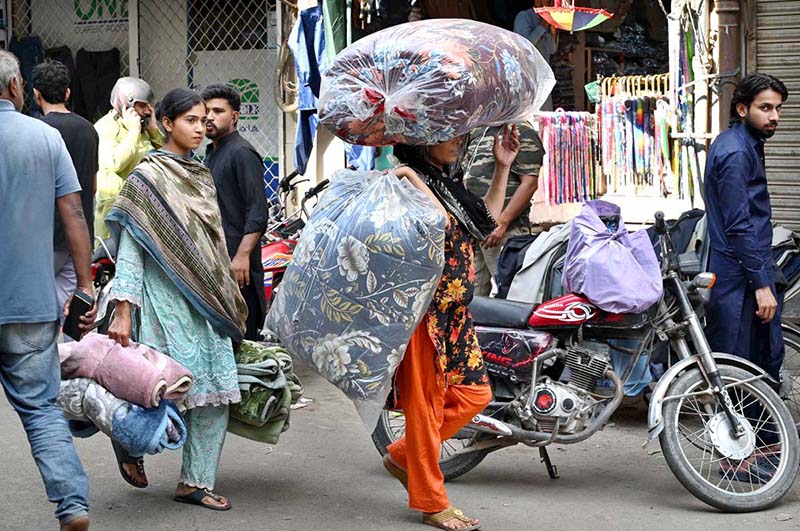 A woman carries cotton-filled quilts (razais) as the weather begins to turn cooler in the city