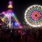 People watch and enjoying a Ferris wheel at night with colorful light during a Dada Hanjer Pir local mela festival at fair ground near Multan road