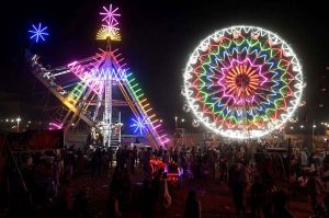 People watch and enjoying a Ferris wheel at night with colorful light during a Dada Hanjer Pir local mela festival at fair ground near Multan road