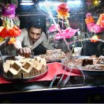 A street vendor is displaying sweets and traditional Sohan Halwa on a handcart to attract customers at road side setup in the City