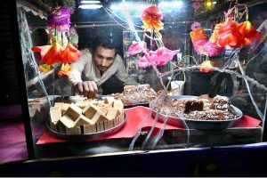 A street vendor is displaying sweets and traditional Sohan Halwa on a handcart to attract customers at road side setup in the City