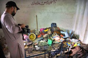 A Rescue 1122 official collects the belongings of schoolchildren from the rubble of a collapsed school building in Dir Colony, where several students were killed and injured.