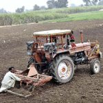 A farmer levels his field with a tractor in preparation for the next crop