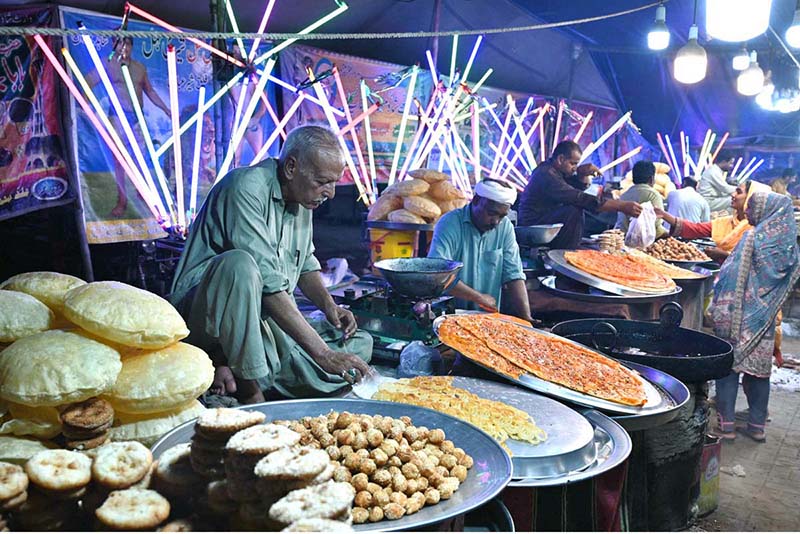 Vendors preparing and display the different kinds of traditional food items to the customer on the roadside colorful stalls during a Dada Hanjer Pir local mela festival at fair ground near Multan road