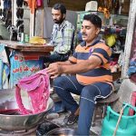A dyer dyes a woman’s dupatta at his workplace