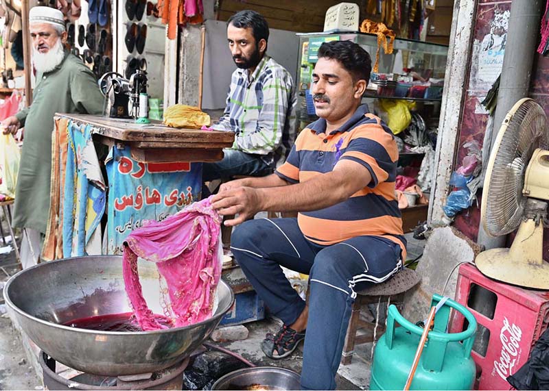 A dyer dyes a woman’s dupatta at his workplace
