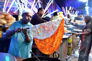 Vendors preparing and display the different kinds of traditional food items to the customer on the roadside colorful stalls during a Dada Hanjer Pir local mela festival at fair ground near Multan road