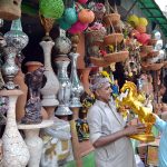 A shopkeeper shows a golden horse statue to a customer at his decorative items shop near Kalma Chowk