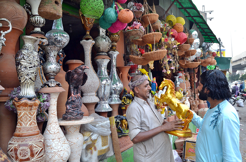 A shopkeeper shows a golden horse statue to a customer at his decorative items shop near Kalma Chowk