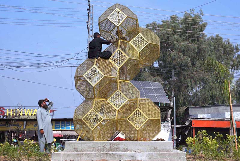 Municipal employees install an ornamental structure to enhance the beauty of area near Hayatabad Toll Plaza