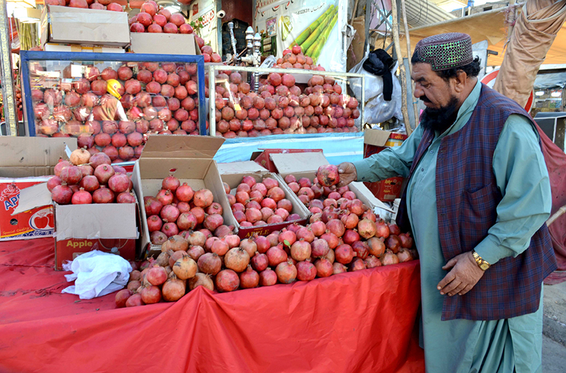 A vendor decorates pomegranates to attract customers at Meezan Chowk