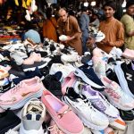 People browse and purchase second-hand shoes from vendors at Landa Bazaar in the provincial capital