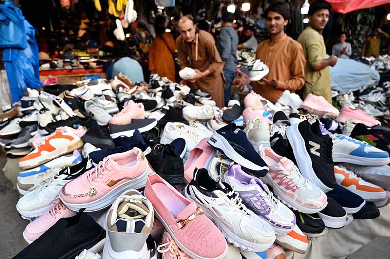 People browse and purchase second-hand shoes from vendors at Landa Bazaar in the provincial capital