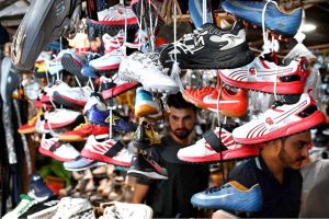People browse and purchase second-hand shoes from vendors at Landa Bazaar in the provincial capital