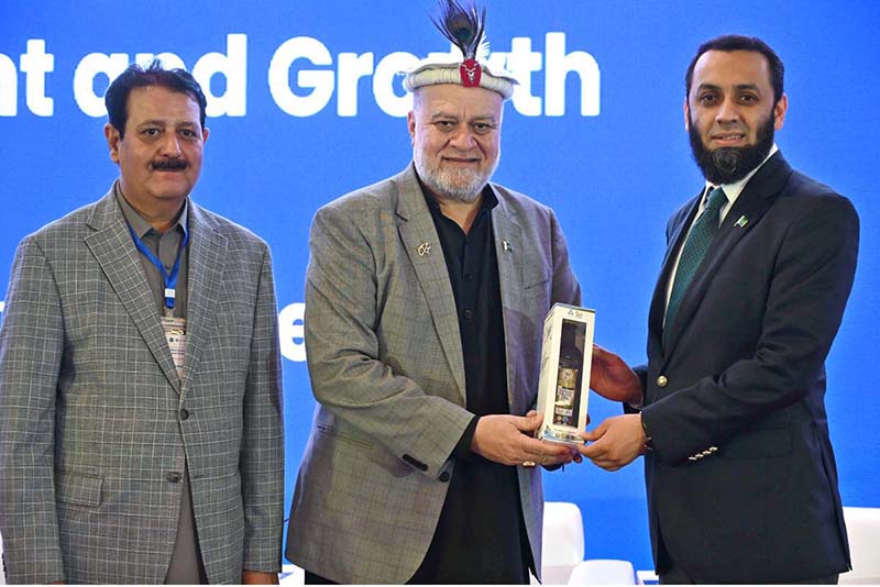 Federal Minister for Poverty Alleviation and Social Safety, Syed Imran Ahmed Shah presenting gift to Federal Minister for Information and Broadcasting, Attaullah Tarar during the International Conference on "Inclusive and Resilient Economic Empowerment and Growth" organized by Pakistan Poverty Alleviation Fund (PPAF) at local hotel