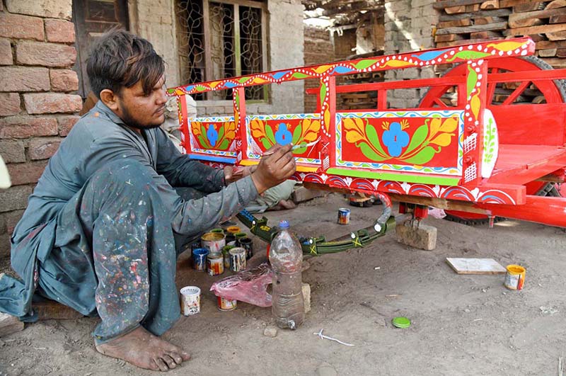 A worker paints a donkey cart at his workplace near Peer Sher Road