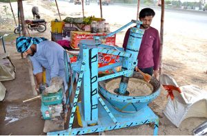A vendor preparing traditional summer drink (sardai) for customers at his roadside setup.