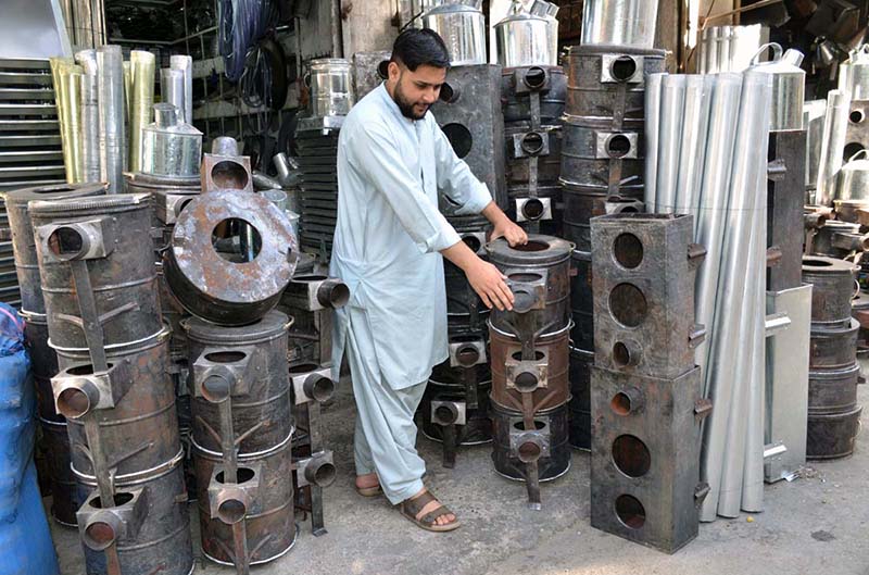 Man displaying traditional stoves as per increased demand in winter season at Surajganj Bazaar