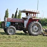 A CDA worker uses a tractor-mounted mower to trim grass along the green belt at Faizabad Interchange