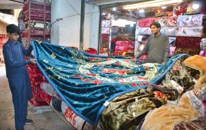 A shopkeeper displays blankets for sale at his shop ahead of the winter season.