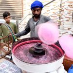 A vendor prepares cotton candy for children on a street in Dari Mohalla