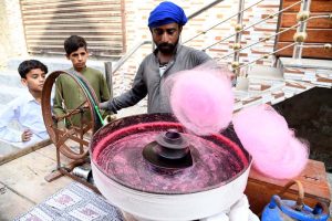 A vendor prepares cotton candy for children on a street in Dari Mohalla