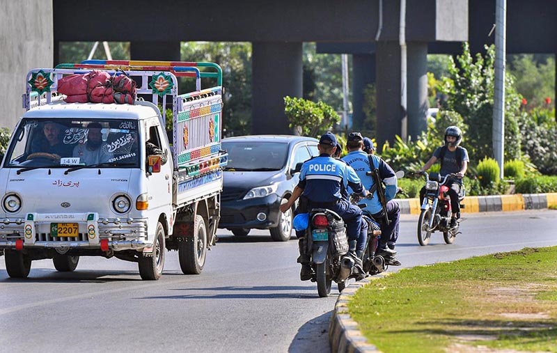 Police official ride their motorcycles against the flow of traffic without wearing safety helmets at Rawal Dam Chowk which sheer violation of traffic rules