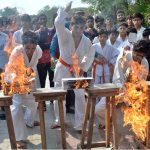 Martial arts players demonstrate their skills to break fire bricks during the opening ceremony of the Inter-Collegiate Boys’ Hockey Tournament at the Astroturf Hockey Stadium, Mela Mandi