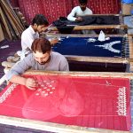 Artisans are hand-embroidering wedding attire at a workshop near Lakshmi Chowk