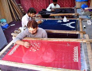 Artisans are hand-embroidering wedding attire at a workshop near Lakshmi Chowk