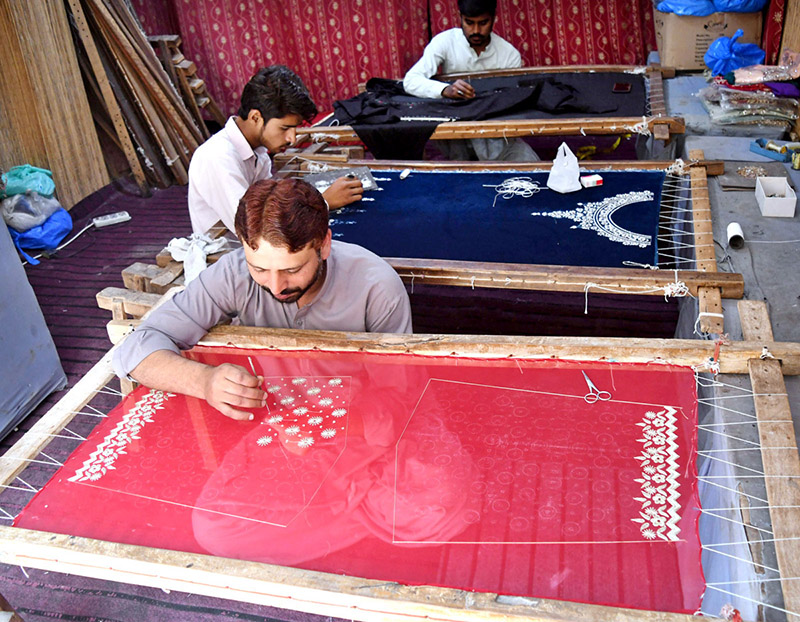 Artisans are hand-embroidering wedding attire at a workshop near Lakshmi Chowk