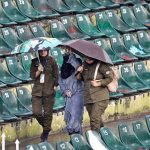 Women police officials shield themselves with umbrellas from the rain before the start of the third T20 cricket match between Pakistan and Sri Lanka at Rawalpindi Cricket Stadium