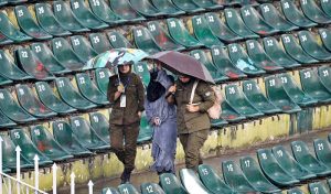 Women police officials shield themselves with umbrellas from the rain before the start of the third T20 cricket match between Pakistan and Sri Lanka at Rawalpindi Cricket Stadium