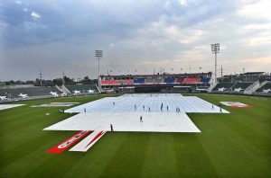 Women police officials shield themselves with umbrellas from the rain before the start of the third T20 cricket match between Pakistan and Sri Lanka at Rawalpindi Cricket Stadium
